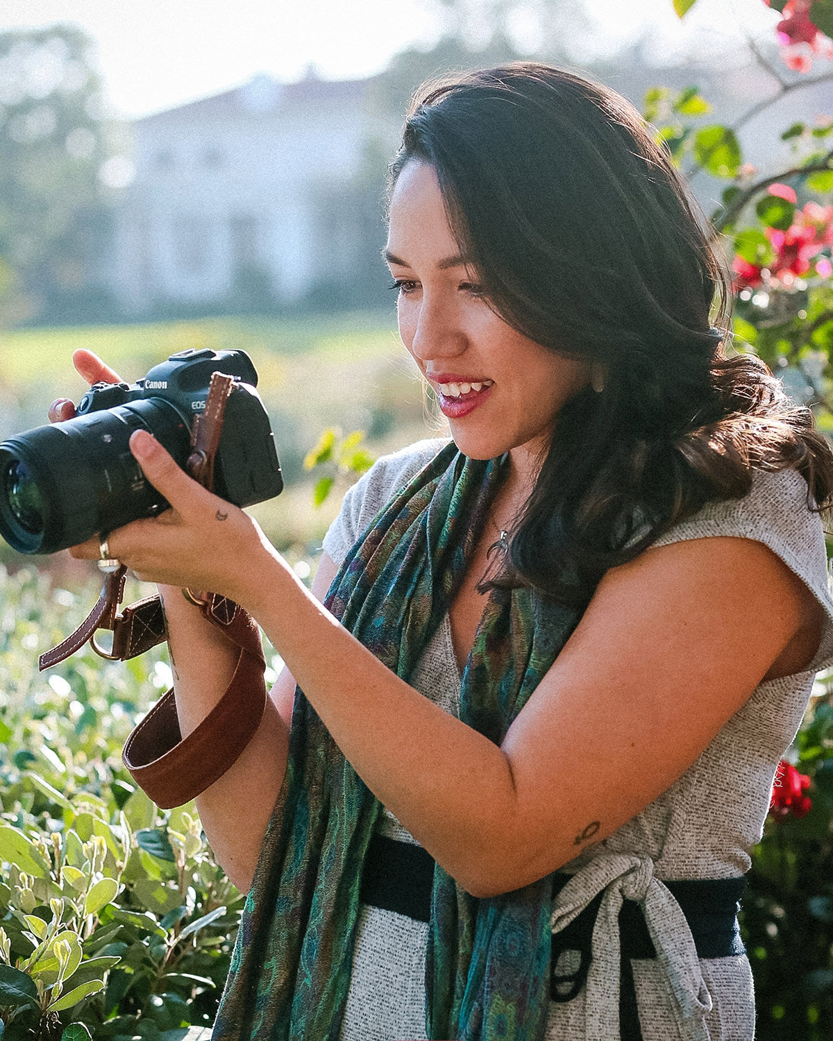Brenda holding a camera in a garden, smiling as she reviews the back of the camera